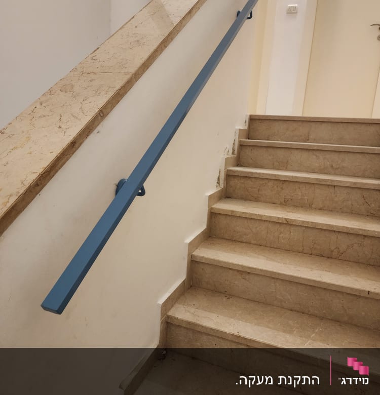 מעקה כחול מותקן על קיר מדרגות שיש